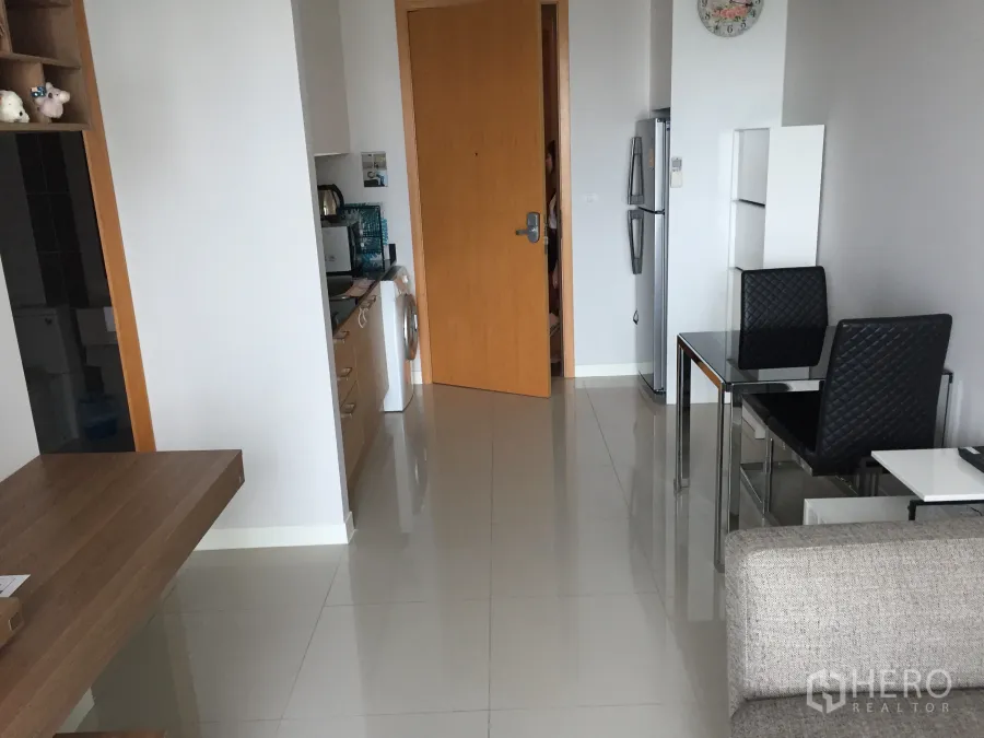 公寓 出租在Ratchathewi, Bangkok - 明亮客厅与开放式小厨房，配冰箱、洗衣机和玻璃餐桌，亮面地砖清爽。