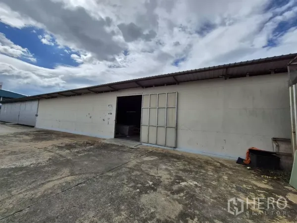 货栈 出租在Mueang Pathum Thani, Pathum Thani - 地面层仓库正面，手动折叠门开启，装卸区宽敞。