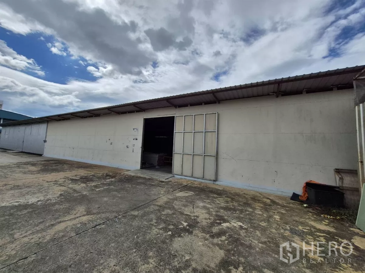 货栈 出租在Mueang Pathum Thani, Pathum Thani - 地面层仓库正面，手动折叠门开启，装卸区宽敞。