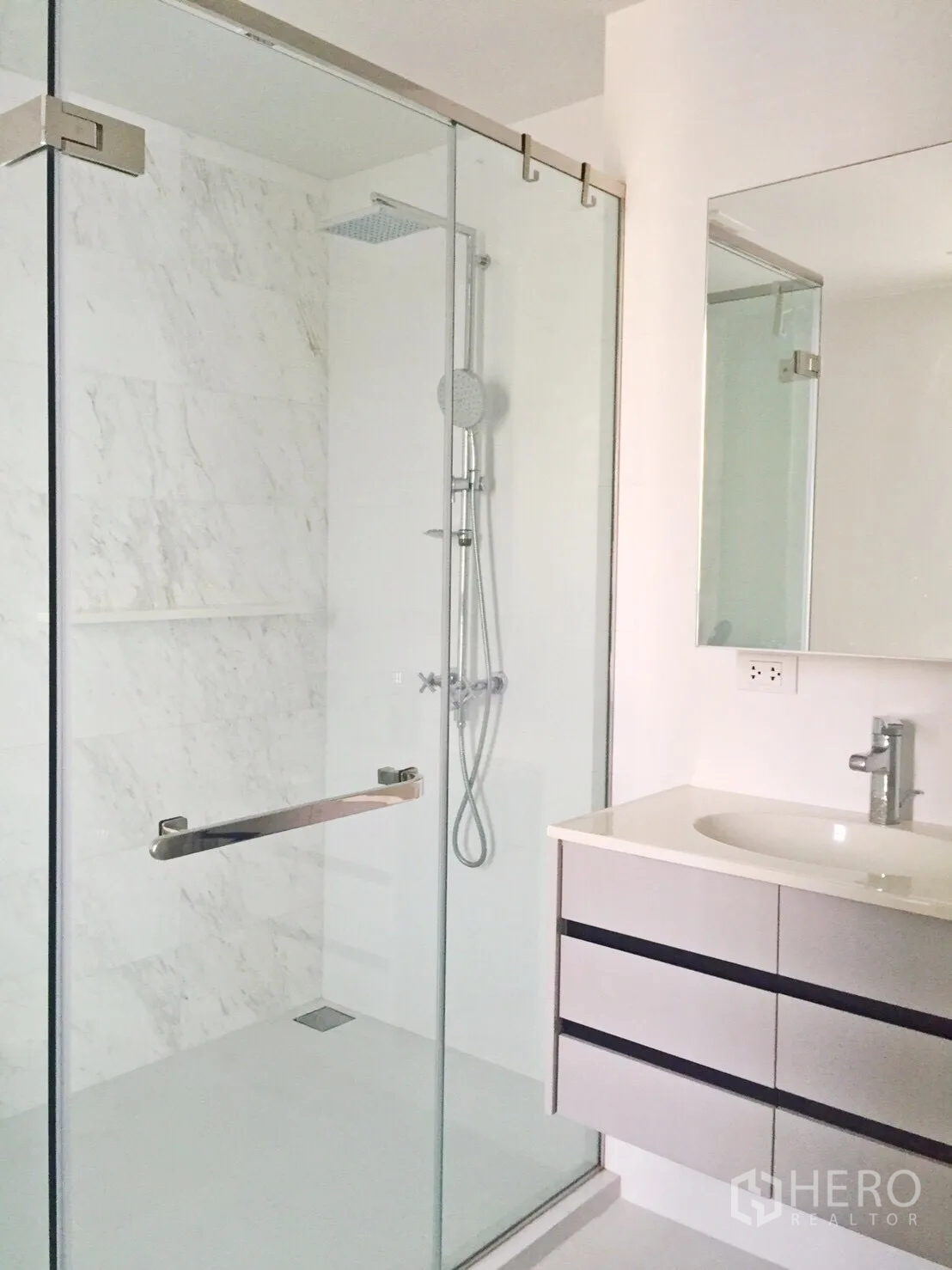 公寓 出租或出售在Watthana, Bangkok - 简洁浴室，玻璃隔断雨淋花洒，悬挂式洗手台与大镜面，白色大理石质感。