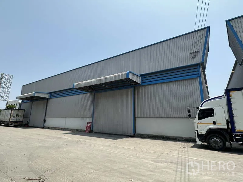 คลังสินค้า ให้เช่าในBang Phli, Samut Prakan - มุมมองด้านข้างโกดัง มีประตูม้วนขนาดใหญ่ ชายคาโหลดสินค้า และทางรถบรรทุก