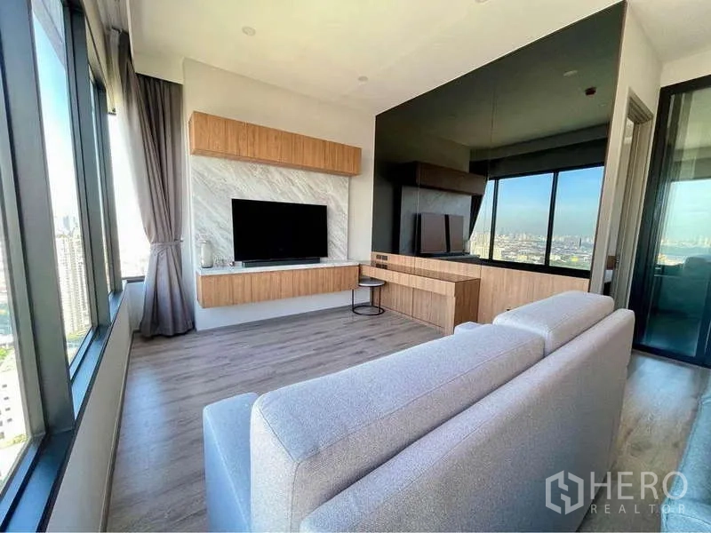 公寓 出租在Watthana, Bangkok - 明亮客厅，环窗全景，悬挂式电视柜及带镜面墙的内置书桌。