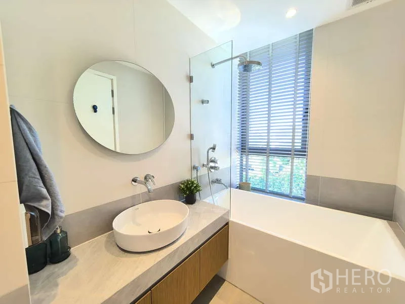 อพาร์ทเมนท์ ให้เช่า - ห้องน้ำพร้อมอ่างอาบน้ำ ฉากกั้นกระจก และกระจกกลมข้างหน้าต่าง