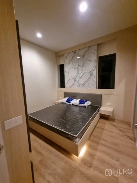Townhouse for rent - Bedroom showcasing a marble-pattern feature wall, under-bed ambient lighting and two narrow windows.
