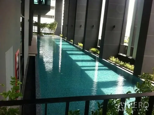 Condominium for rent in Huai Khwang, Bangkok - Condominium lap pool with shaded deck, tall columns and greenery.