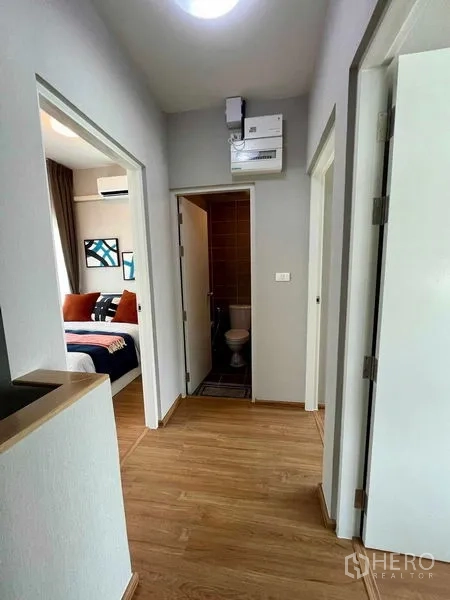 Townhouse for sale in Sai Mai, Bangkok - Upper hallway with shared bathroom between two bedrooms and wood flooring.
