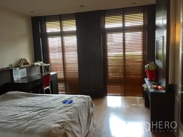 Condominium for rent in Watthana, Bangkok - Guest bedroom featuring study desk, polished wood floor and full-height wooden blinds to a balcony.