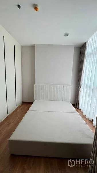 คอนโด ให้เช่าในBang Na, Bangkok - ห้องนอนสไตล์มินิมอล ฐานเตียงบิวท์อิน ตู้เสื้อผ้าบิลท์อิน และหน้าต่างสูงพร้อมผ้าม่าน