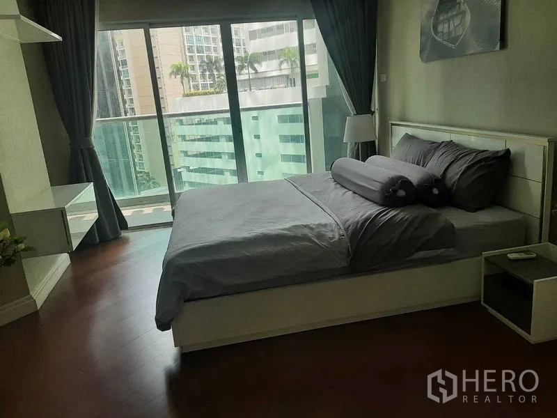 Condominium for rent or sale in Huai Khwang, Bangkok - Master bedroom with floor-to-ceiling windows, balcony access, and city views.