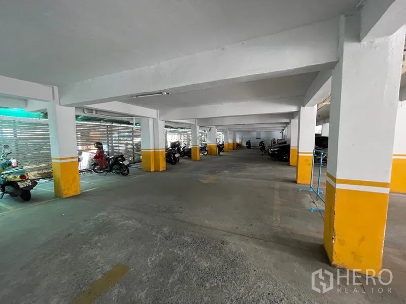 Apartment for sale in Mueang Samut Prakan, Samut Prakan - Indoor car and motorbike parking area with concrete pillars and yellow markings.