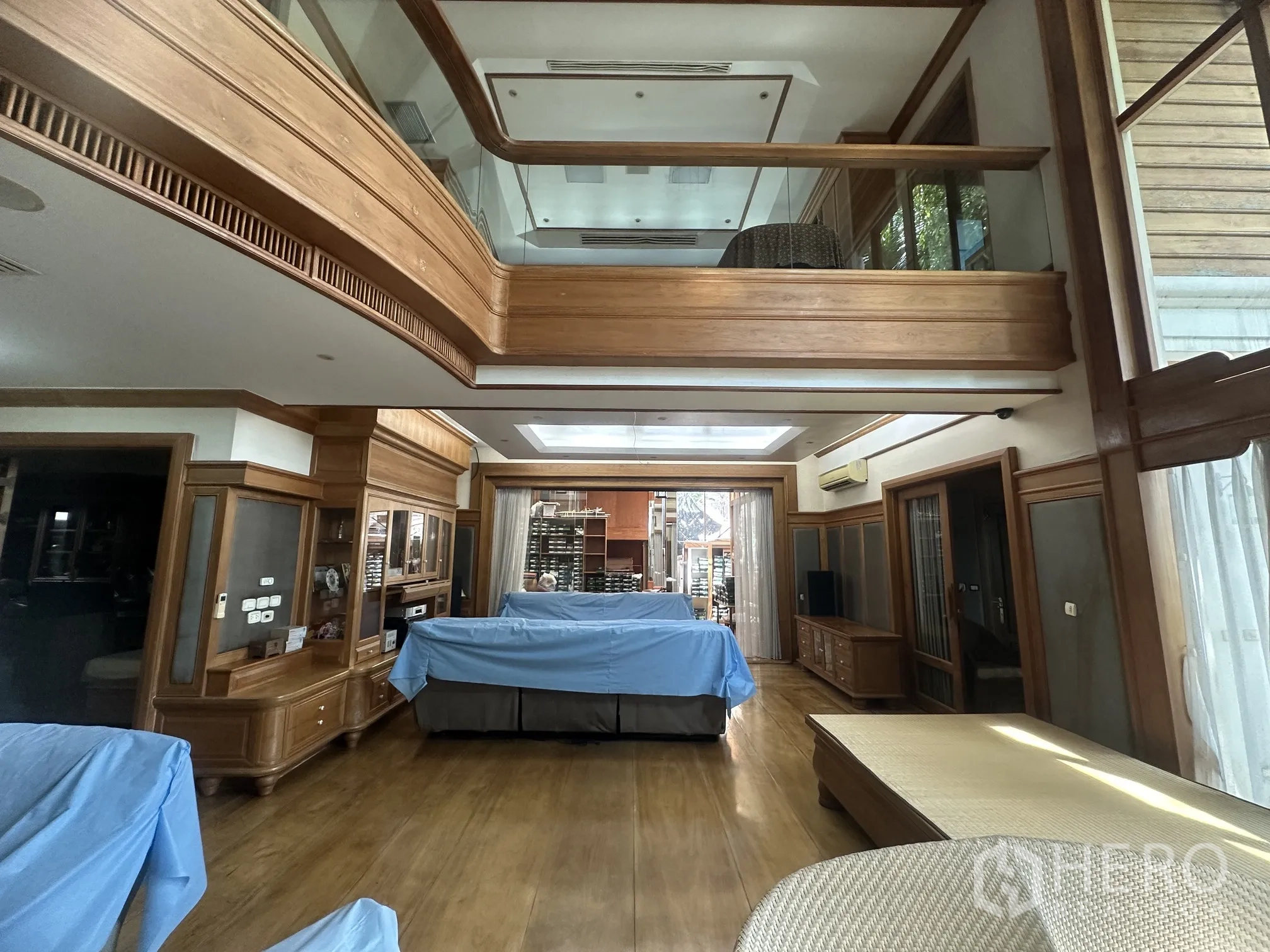 Detached House for rent in Lam Luk Ka, Pathum Thani - Spacious living room with double-height void, wood built-ins, and large windows.