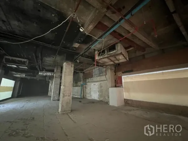 零售空间 出租在Bang Rak, Bangkok - 长方形零售区域，墙面为粗糙混凝土并可见管线。