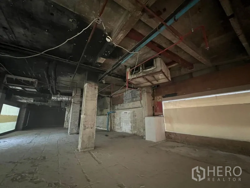 零售空间 出租在Bang Rak, Bangkok - 长方形零售区域，墙面为粗糙混凝土并可见管线。