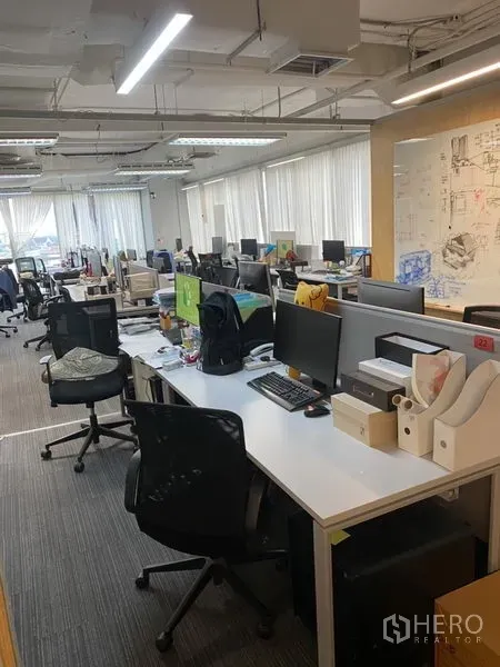 สำนักงาน ให้เช่าในKhlong Toei, Bangkok - ออฟฟิศแปลนเปิด โต๊ะทำงานเรียงหลายแถว ปูพรม และหน้าต่างบานใหญ่พร้อมม่านปรับแสง