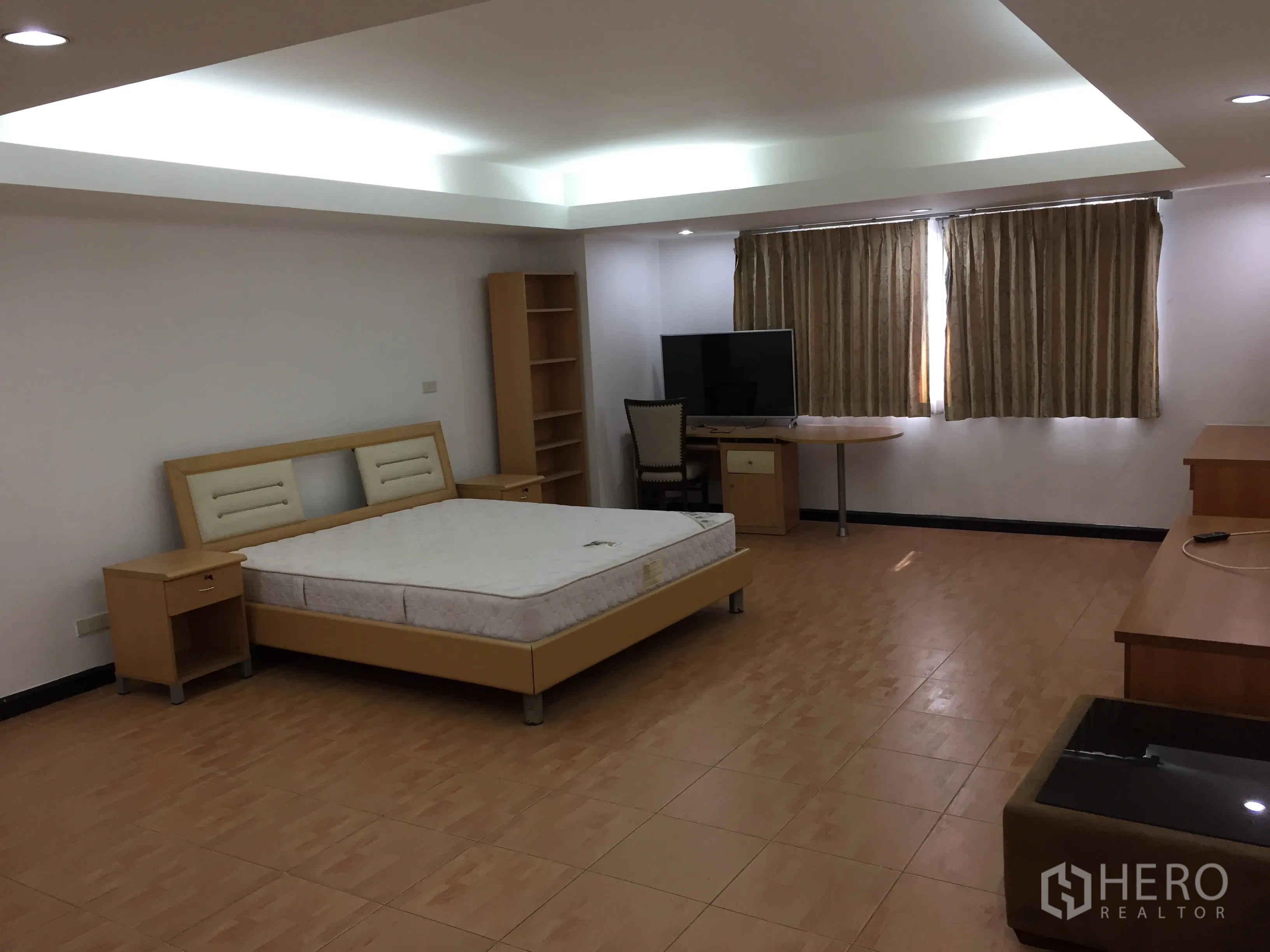 Condominium for rent in Watthana, Bangkok - Spacious master bedroom with bed, TV, work desk, and cove ceiling lighting.