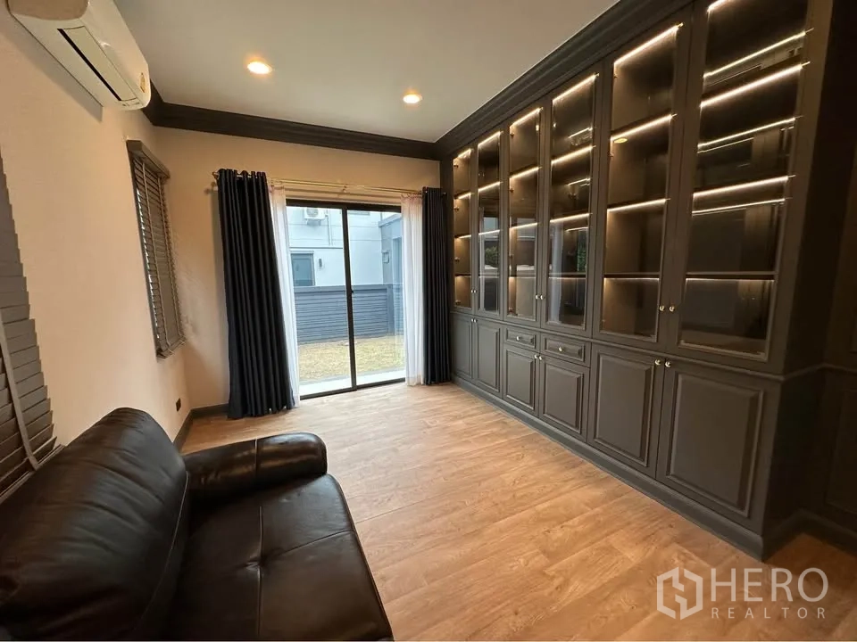 บ้านเดี่ยว for rent in Bang Kapi, Bangkok - มุมห้องเดียวกันมีประตูกระจกออกสู่สนามหญ้าและตู้โชว์บิลต์อิน