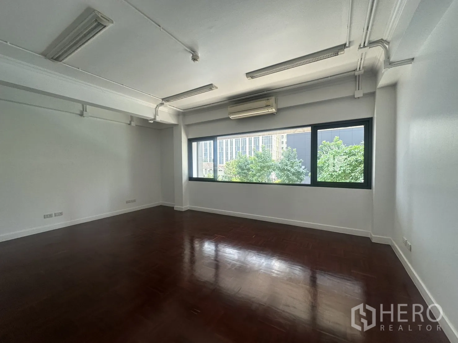 办公室 for rent in Watthana, Bangkok - 大面积办公室，装有空调，窗外可见树景与城市景观。