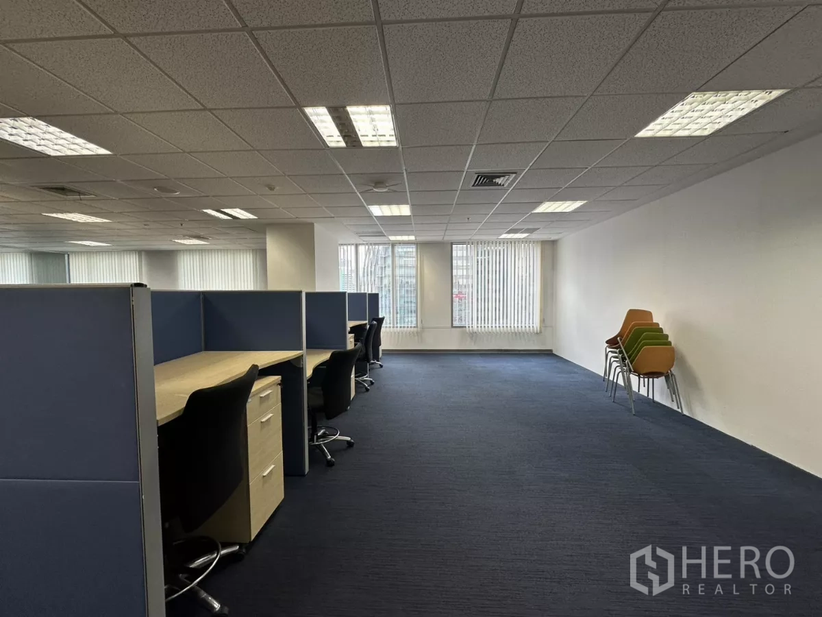 Office Space for rent in Watthana, Bangkok - Work area with cubicles near windows and a stack of visitor chairs.