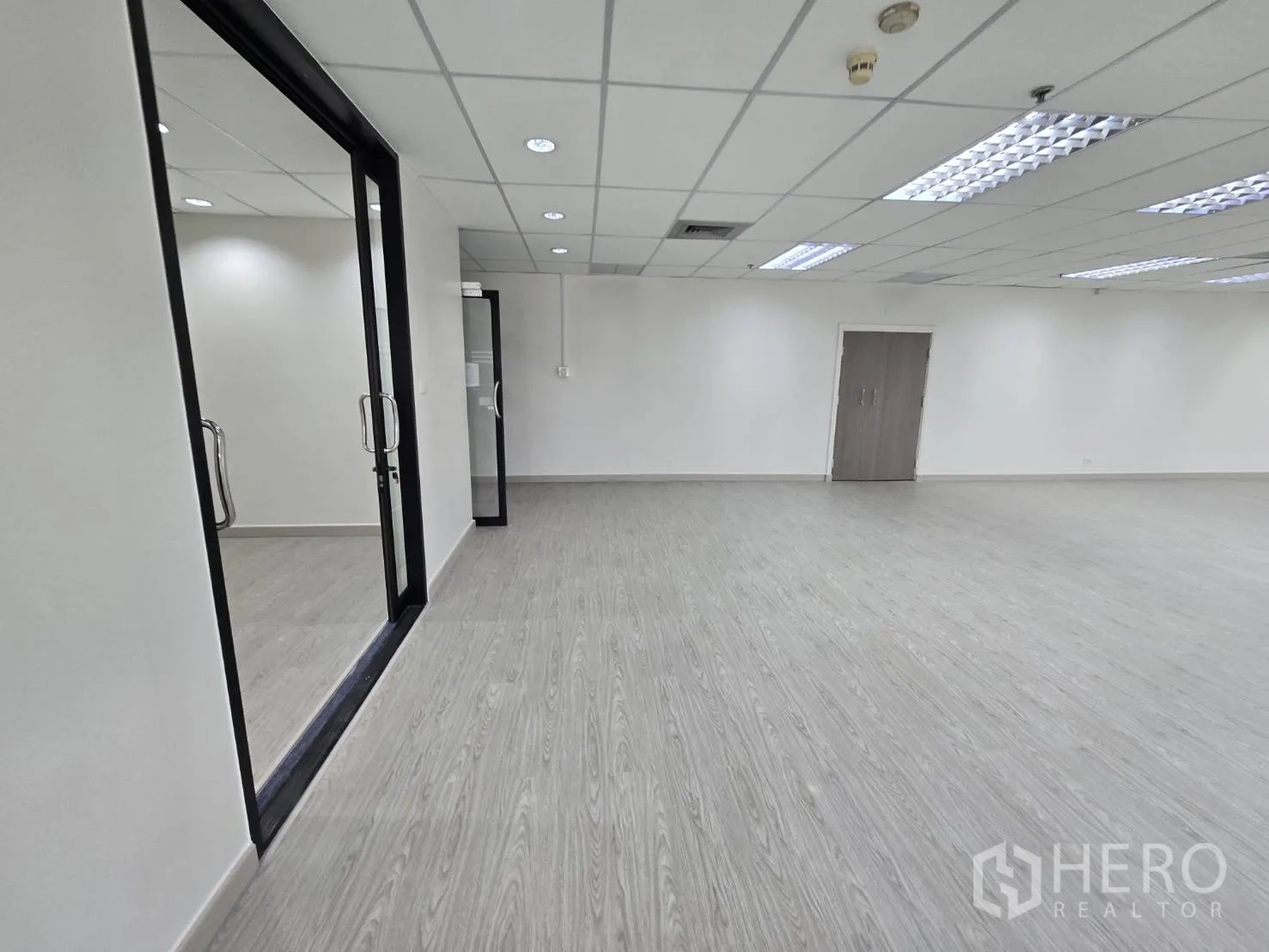 Office Space for rent in Khlong Toei, Bangkok - Interior office area with sliding glass doors and light wood-look flooring.