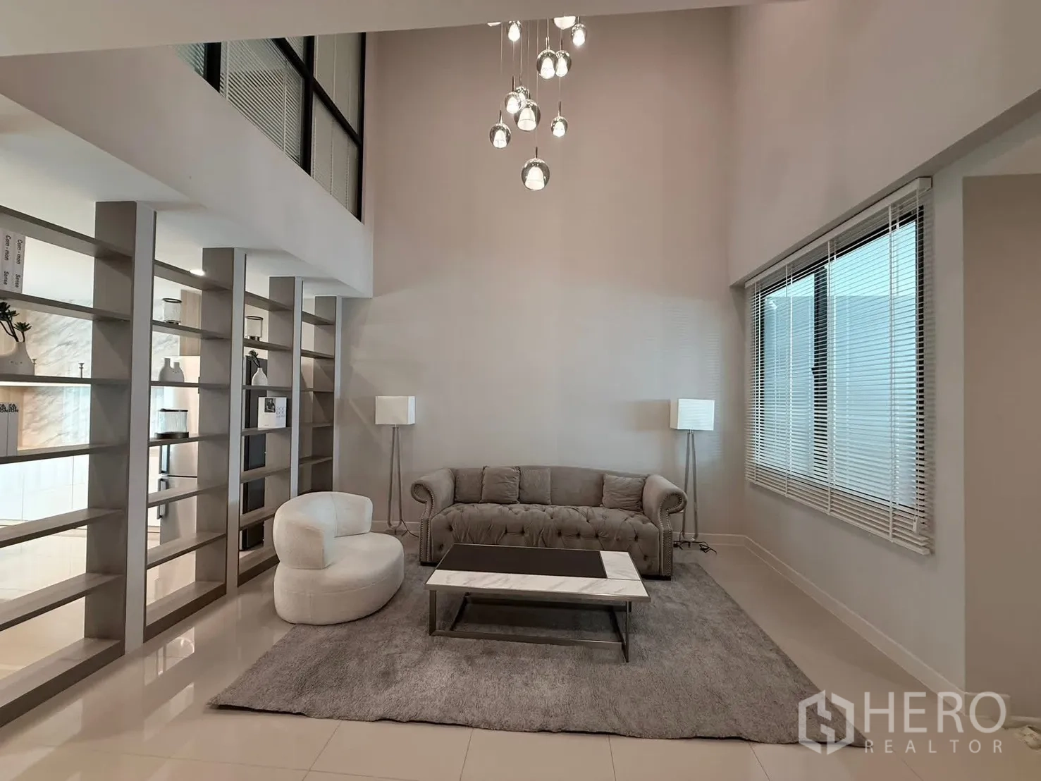 Townhouse for rent in Saphan Sung, Bangkok - Loft-like living area with tall shelves, rug and large window blinds.