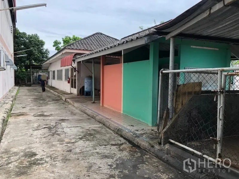 工厂 出售在Lam Luk Ka, Pathum Thani - 单层辅房旁的服务步道，彩色墙面与雨棚