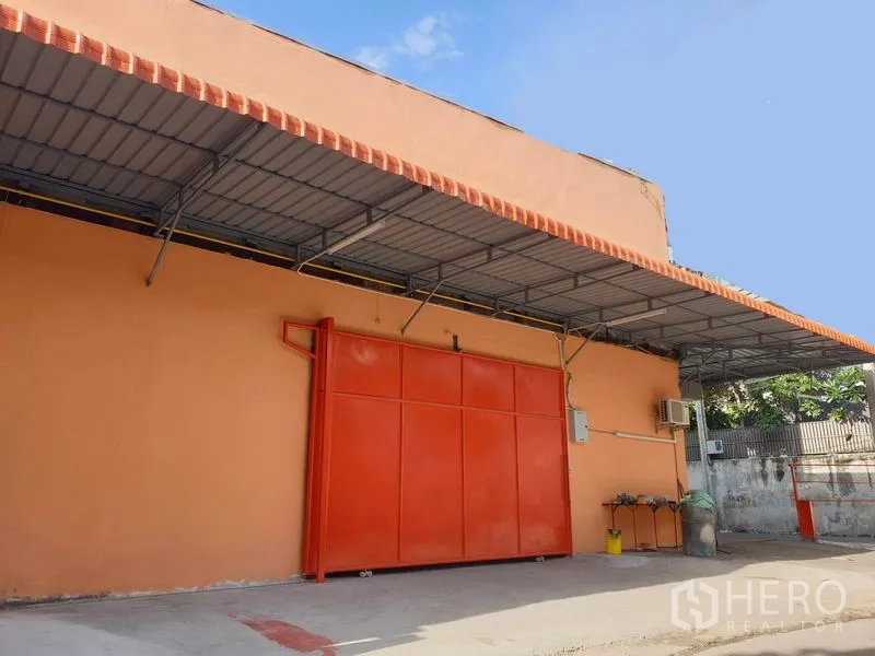 Warehouse for rent in Din Daeng, Bangkok - Orange warehouse exterior with large sliding metal door and a covered loading bay in Din Daeng, Bangkok.