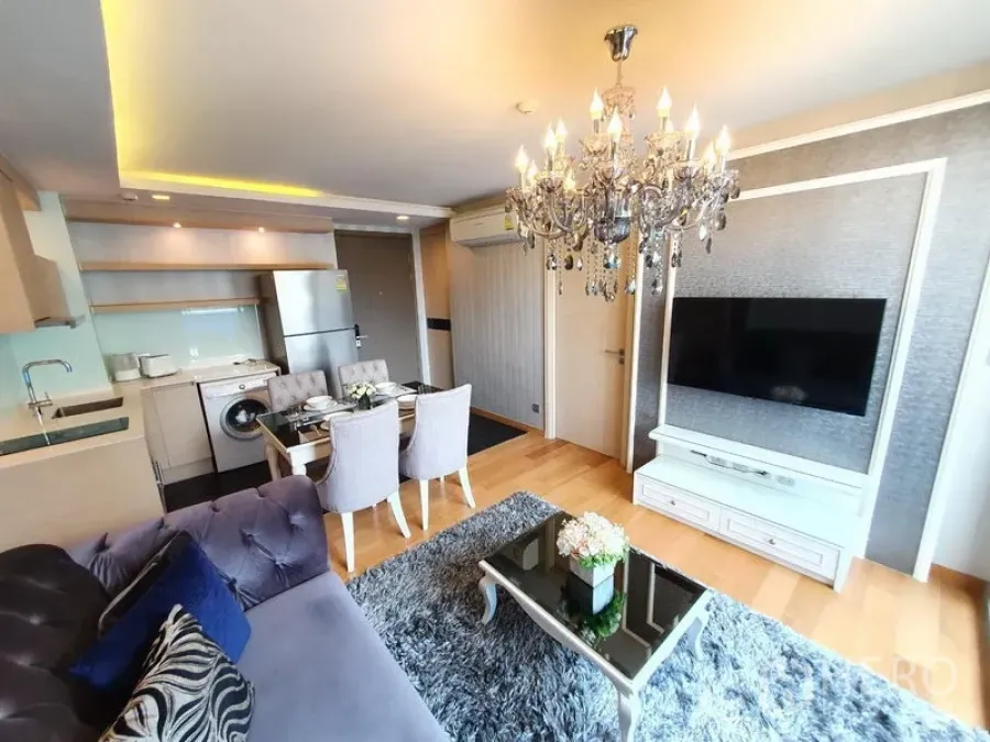 公寓 出租在Watthana, Bangkok - 开放式客厅配水晶吊灯、壁挂电视与紧凑厨房的瓦他那区公寓。