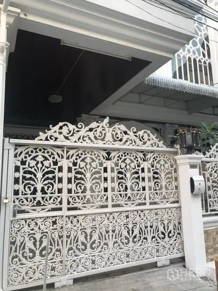 Townhouse for rent in Khlong Toei, Bangkok - Close view of the white wrought‑iron sliding gate and covered carport entrance.