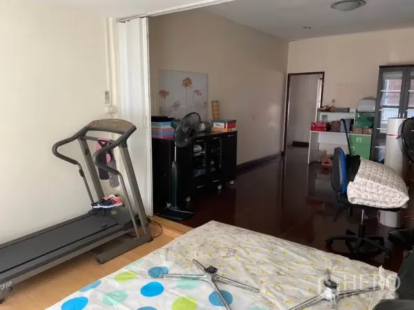 Townhouse for rent in Khlong Toei, Bangkok - Multi-purpose bedroom with wooden floors, treadmill, storage cabinets, and workspace.