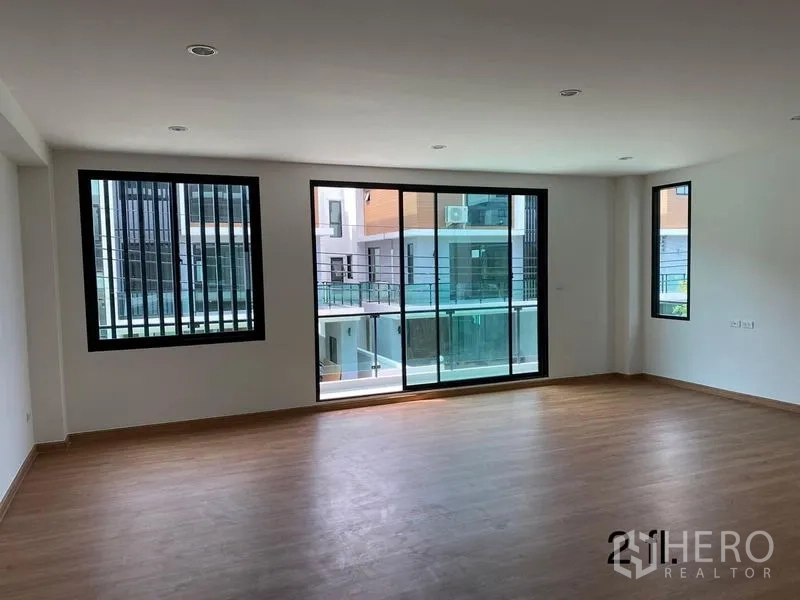 Home Office for rent or sale in Bang Phli, Samut Prakan - Large bedroom or office suite with wood flooring and balcony doors overlooking the development.
