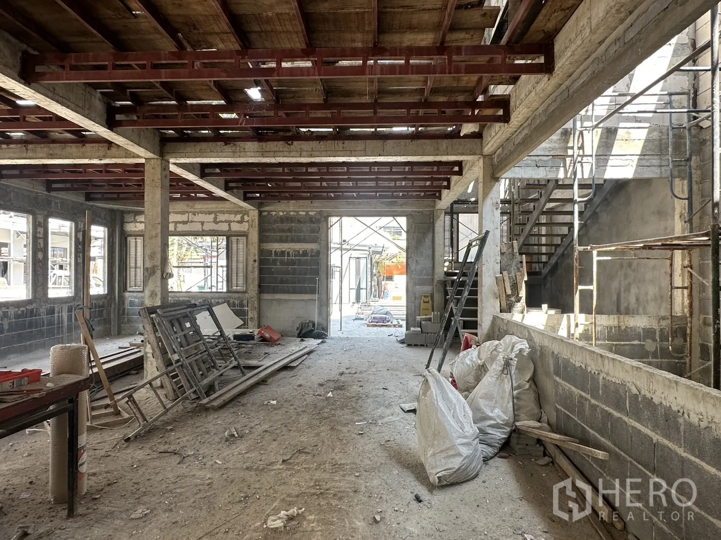 零售空间 for rent in Bang Na, Bangkok - 宽敞大厅，外露梁架与多窗，地面堆放建材。