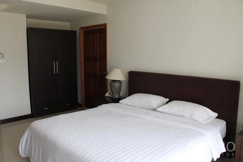 房间 出租在Bang Rak, Bangkok - 卧室另一角度，带衣柜和木门。