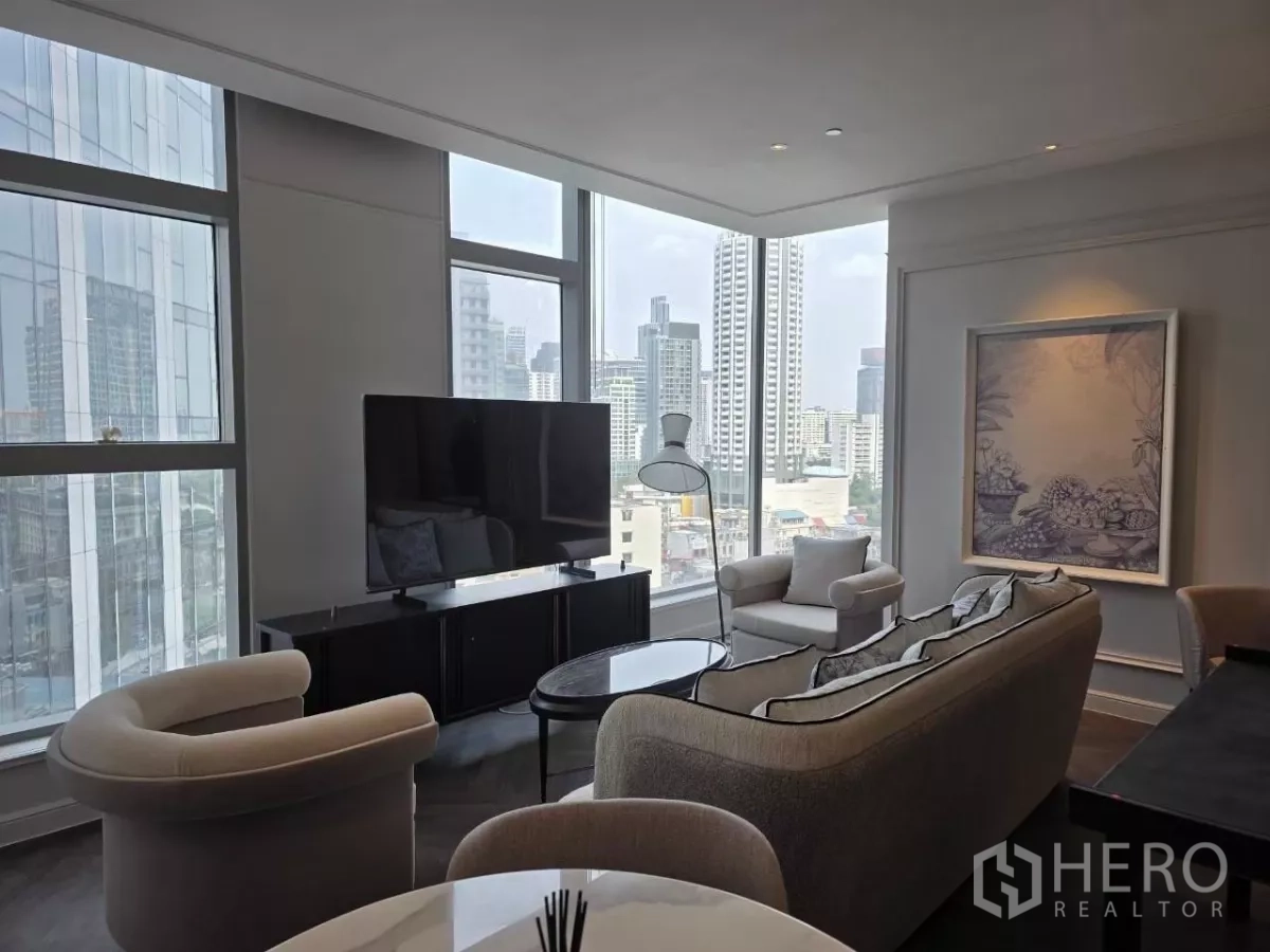 คอนโด ให้เช่า - ห้องนั่งเล่นมุมกระจก มองเห็นสกายไลน์ ทีวีและเก้าอี้โค้ง