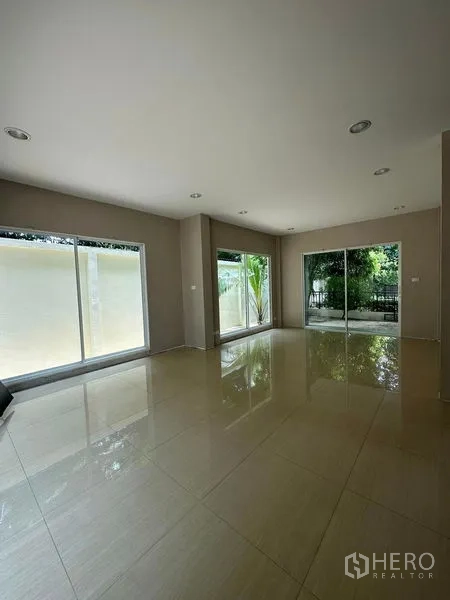 独立式住宅 出售在Prawet, Bangkok - 宽敞客厅，亮面地砖与落地推拉窗连通花园（帕拉威，曼谷）。