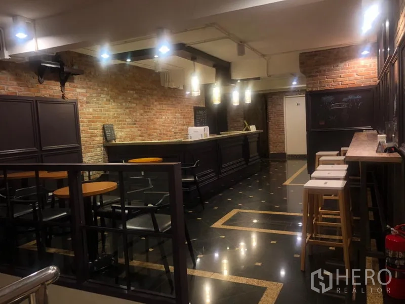 店屋 出租在Watthana, Bangkok - 餐厅吧台内饰，裸露红砖墙、深色木吧台与吊灯、咖啡式座位。