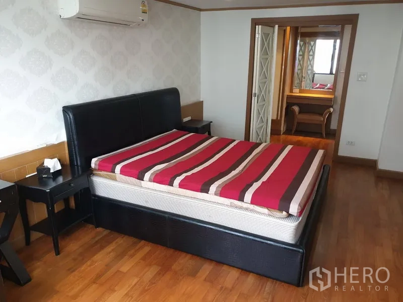 Condominium for rent in Watthana, Bangkok - Primary bedroom with upholstered bed, wallpaper feature wall and access to a dressing area.