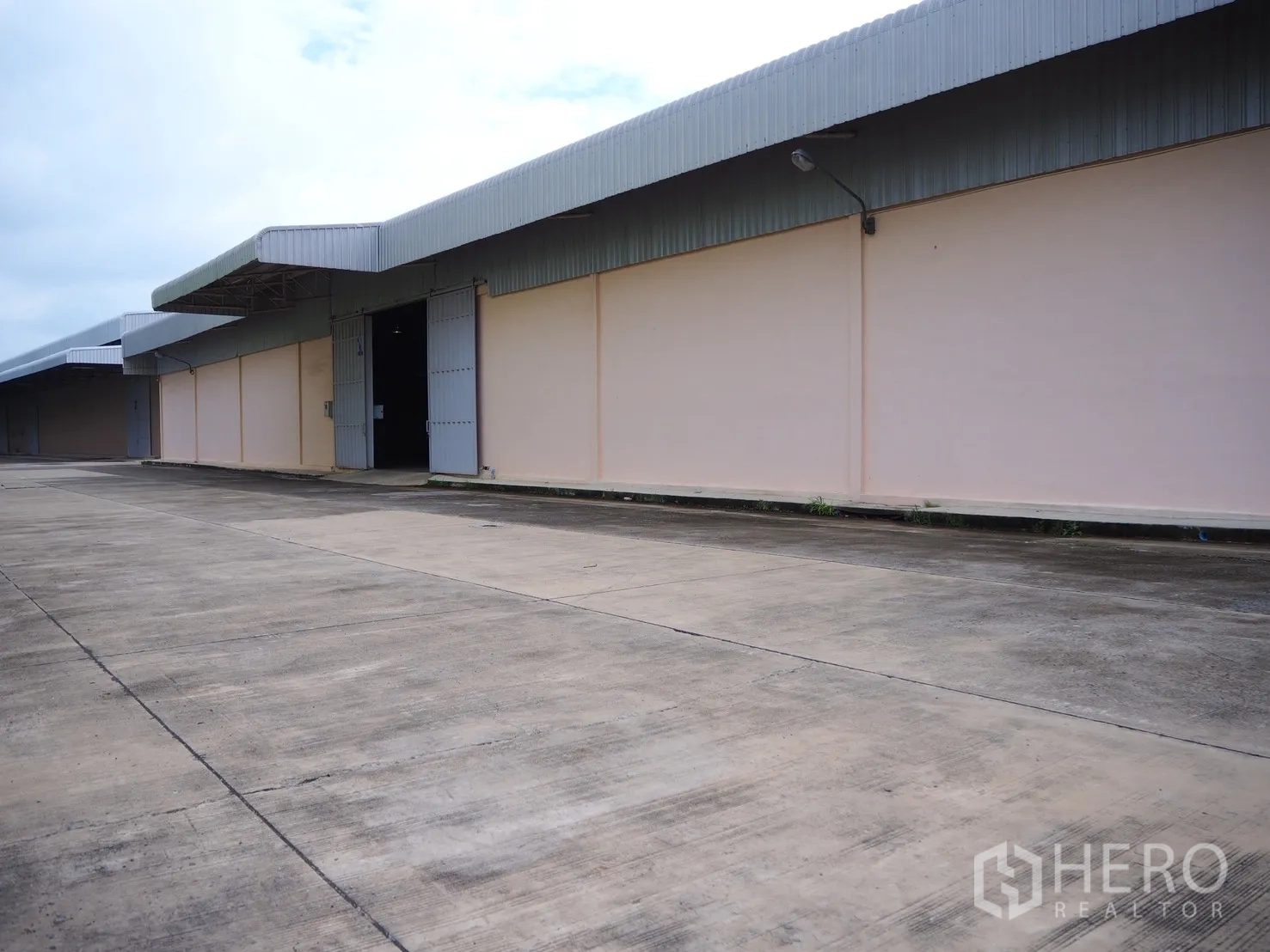 โรงงาน for rent in Uthai, Phra Nakhon Si Ayutthaya - ด้านหน้าโรงงานมีชายคาเมทัลชีท ประตูเหล็กขนาดใหญ่ และลานคอนกรีตกว้างสำหรับรถบรรทุก