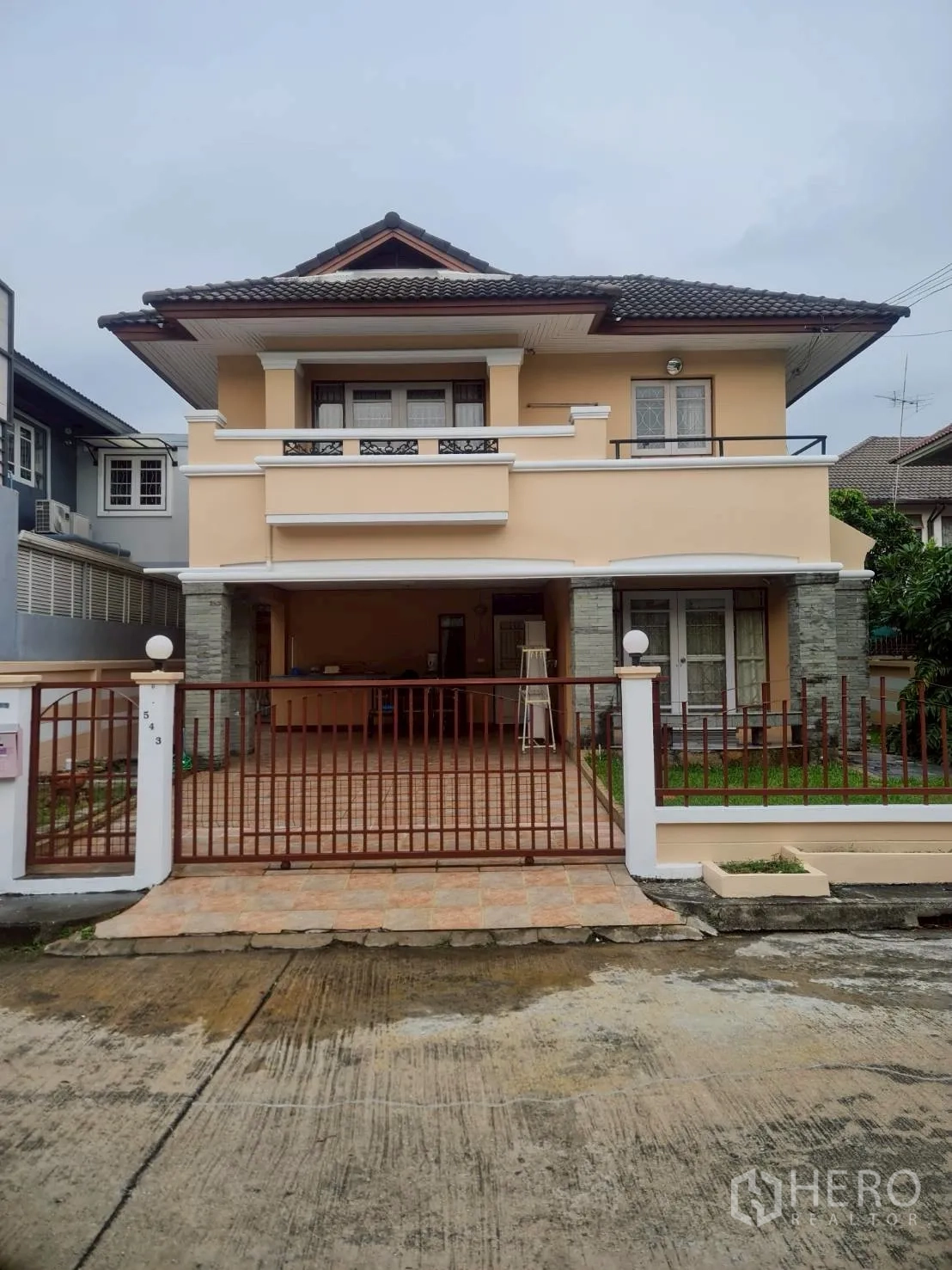 บ้าน ให้เช่าในMin Buri, Bangkok - มุมมองด้านหน้าบ้านเดี่ยวสองชั้นพร้อมระเบียง โรงจอดรถปูกระเบื้อง และรั้วเหล็กในมินบุรี กรุงเทพฯ