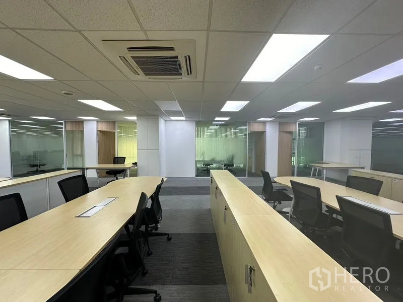 Office Space for rent - Collaborative zone with light-wood partitions, task chairs and glass-walled rooms.