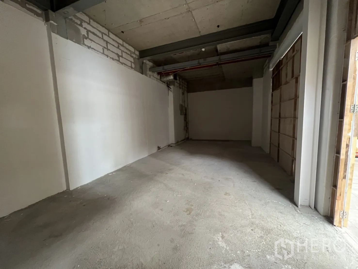 零售空间 出租在Khlong Toei, Bangkok - 狭长的开放式店铺，白色隔墙与裸露梁柱天花。