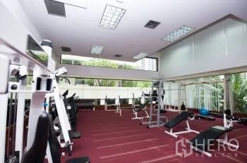 Condominium for sale in Watthana, Bangkok - Fitness center with weight and cardio machines overlooking greenery.