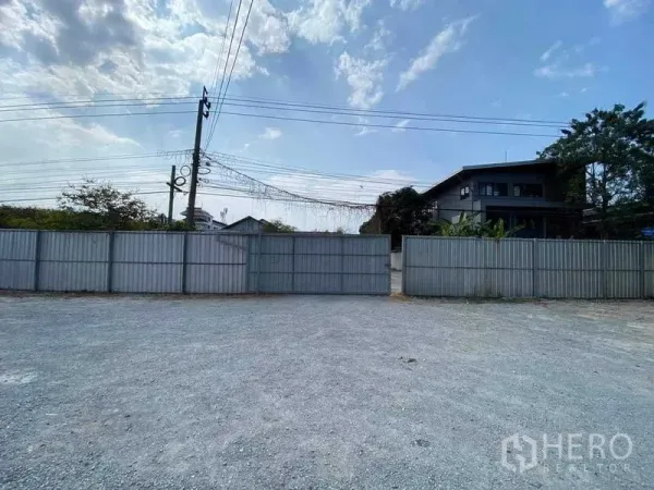 Warehouse for rent in Nong Khaem, Bangkok - Wide gated entrance with metal fence and spacious gravel driveway outside the warehouse.