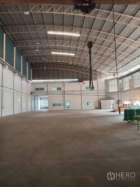 Factory for rent in Mueang Samut Prakan, Samut Prakan - Expansive warehouse-style factory with crane hook, mezzanine offices, and a wide concrete floor.