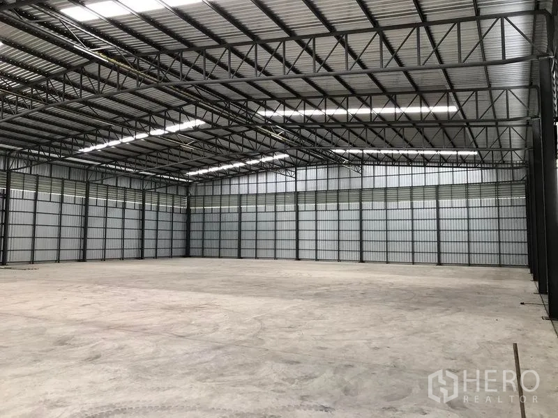 Warehouse for rent in Pathum Thani - Interior corner view of the high-clearance warehouse with steel structure and bright natural lighting.