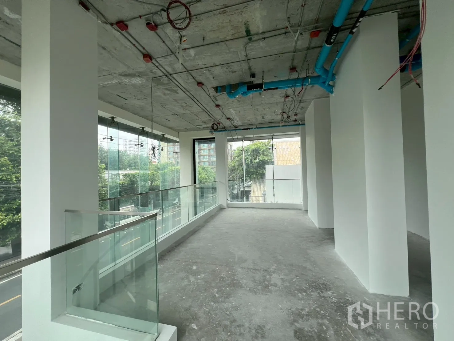พื้นที่ขายปลีก ให้เช่า - ชั้นลอยสว่างพร้อมราวกระจกและงานเดินท่อบนเพดาน