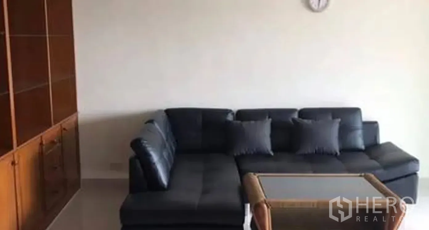 公寓 for sale in Watthana, Bangkok - 客厅内L型黑色皮沙发、玻璃茶几与内置柜。