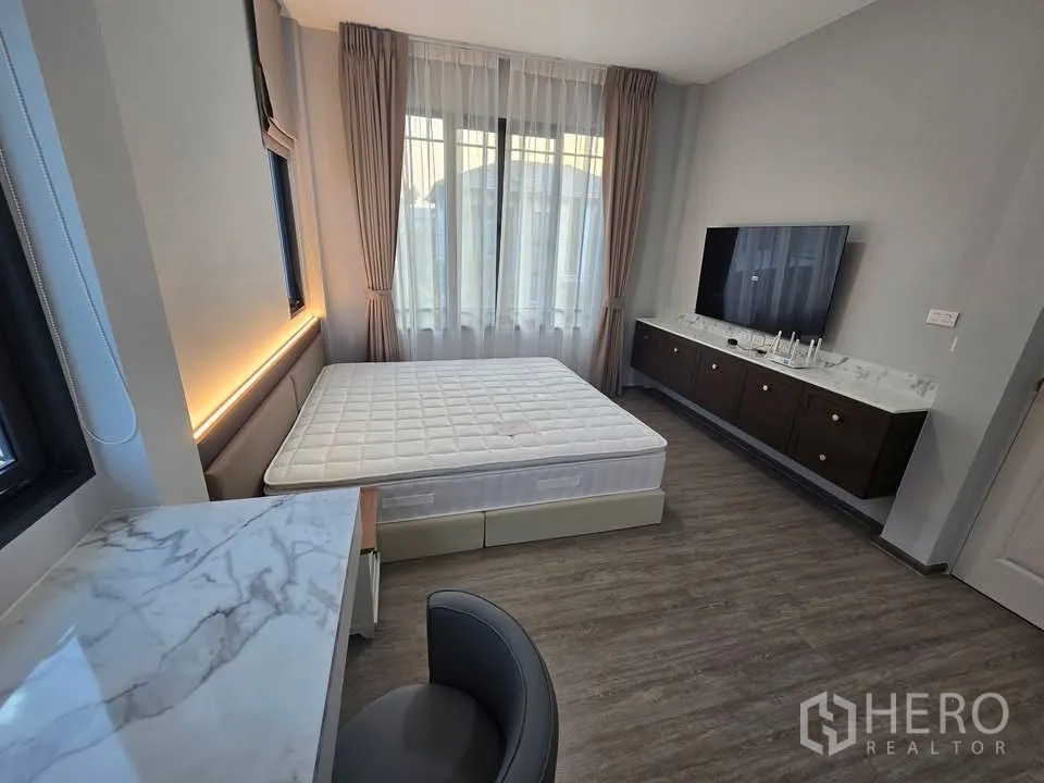 Semi-detached House for rent in Bang Phli, Samut Prakan - Spacious bedroom with large windows, marble-top console, TV, and upholstered bed.