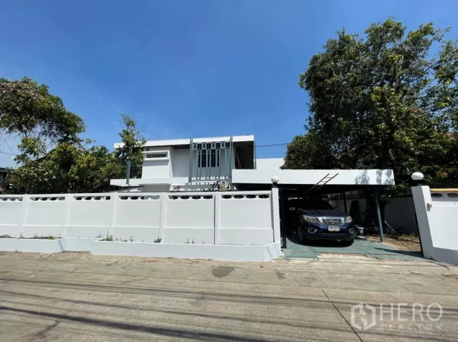 带办公室的家 出租在Din Daeng, Bangkok - 丁登区两层白色家庭办公楼的街景，可见高墙、大门与带顶车棚。