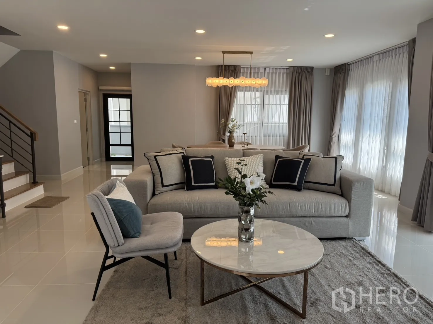 Detached House for rent in Bang Phli, Samut Prakan - Living room featuring gray sofa, round marble coffee table and view to stairs and dining area.