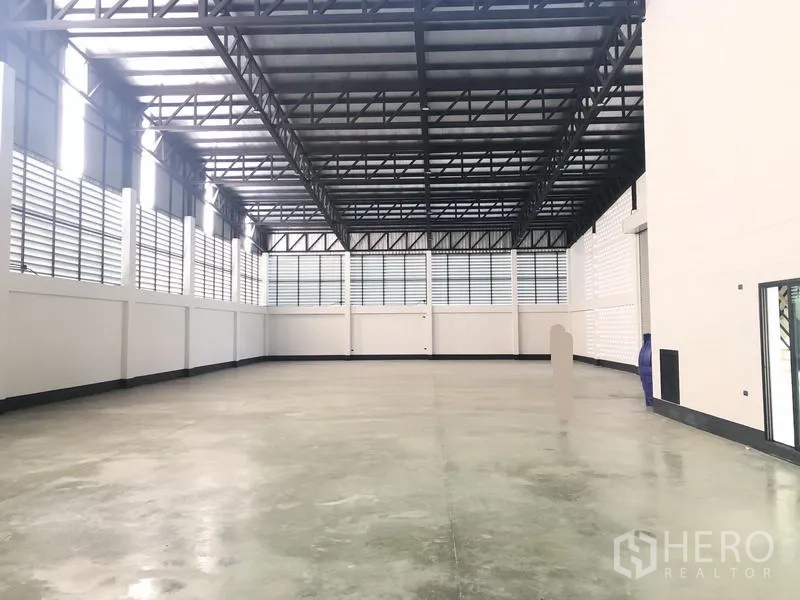 โรงงาน ขายในPathum Thani - ภายในโกดังโล่ง หลังคาทรัสเหล็กสูง พื้นคอนกรีตขัดมัน และช่องลมระบายอากาศ